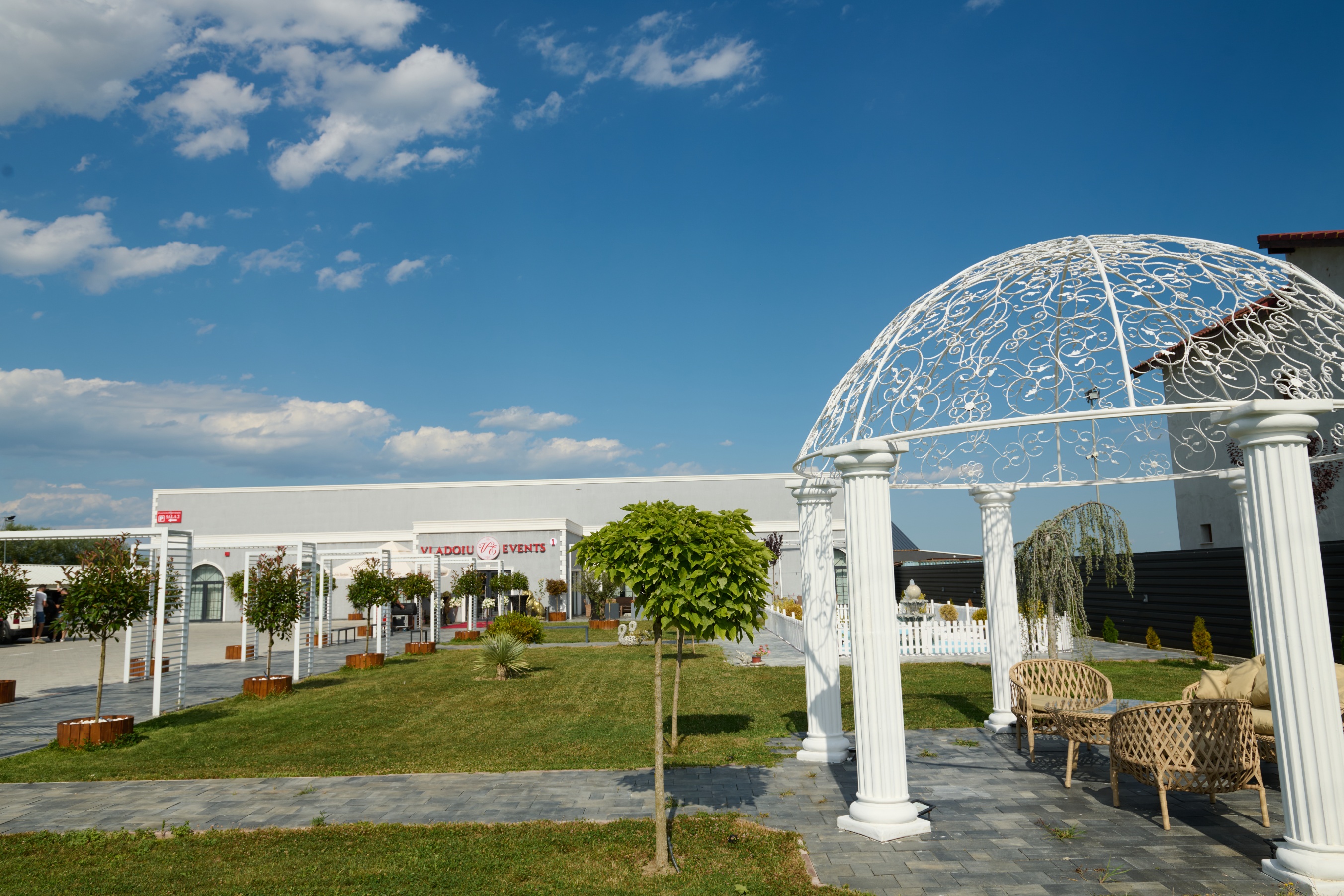 Pergolă albă la intrarea în Vladoiu Events, cu covor roșu