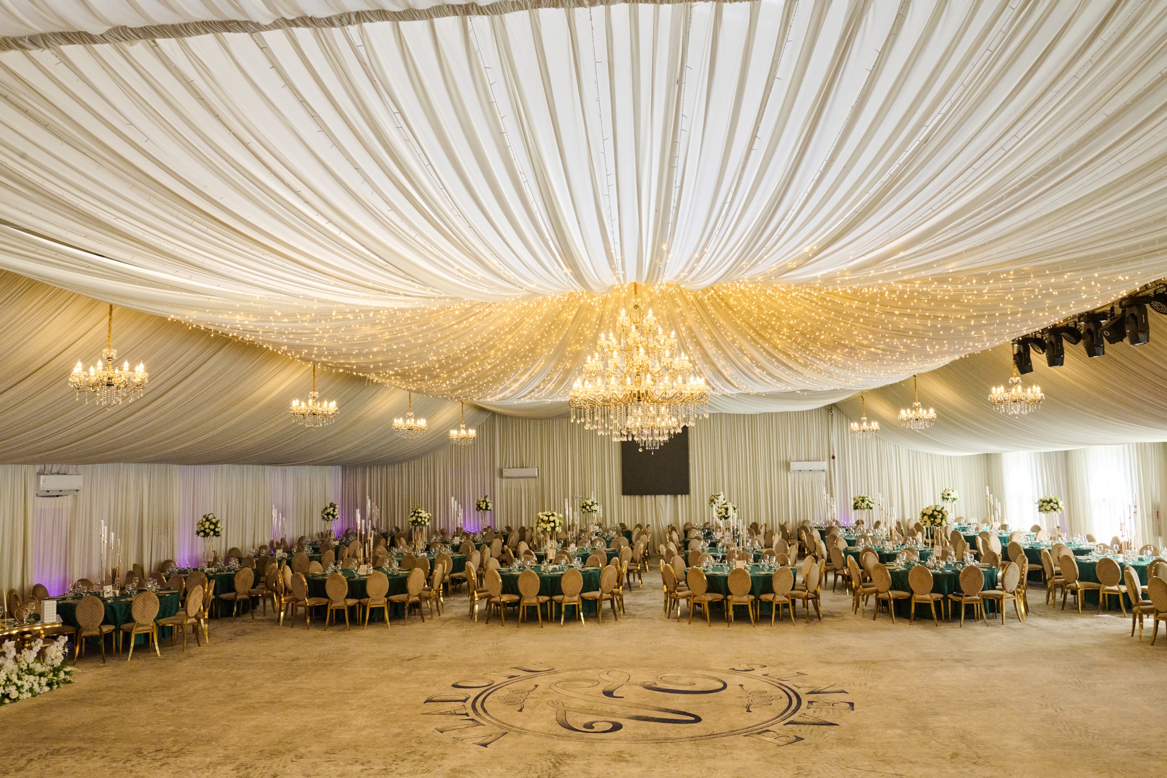 Sala de evenimente cu candelabru auriu masiv și mese verde-smarald